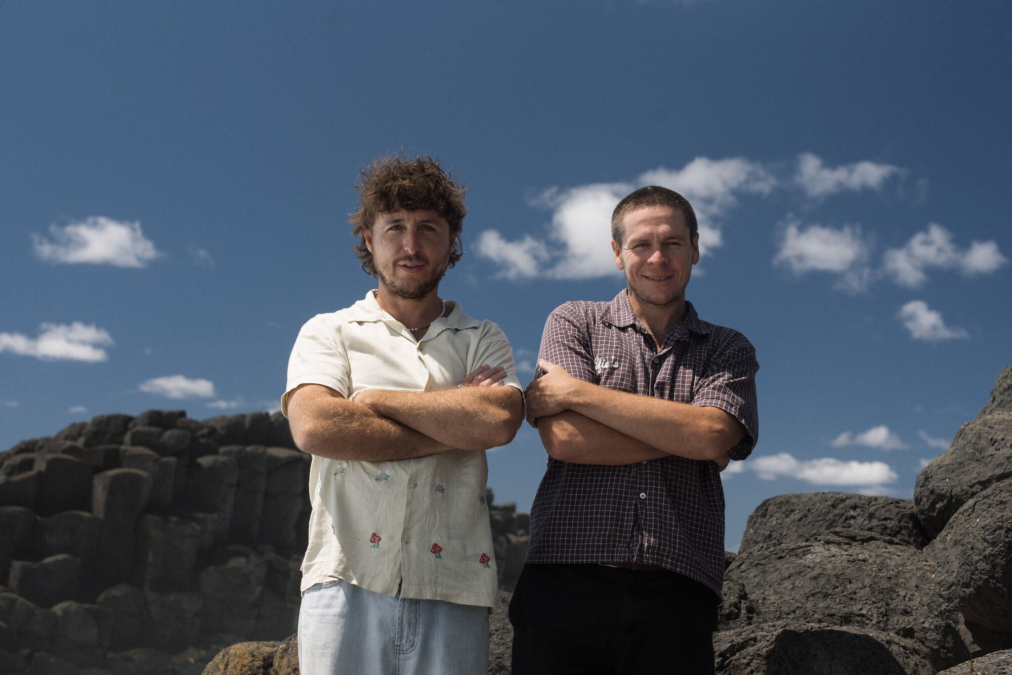 Bali and Benny Benson on the rocks by the ocean, arms crossed